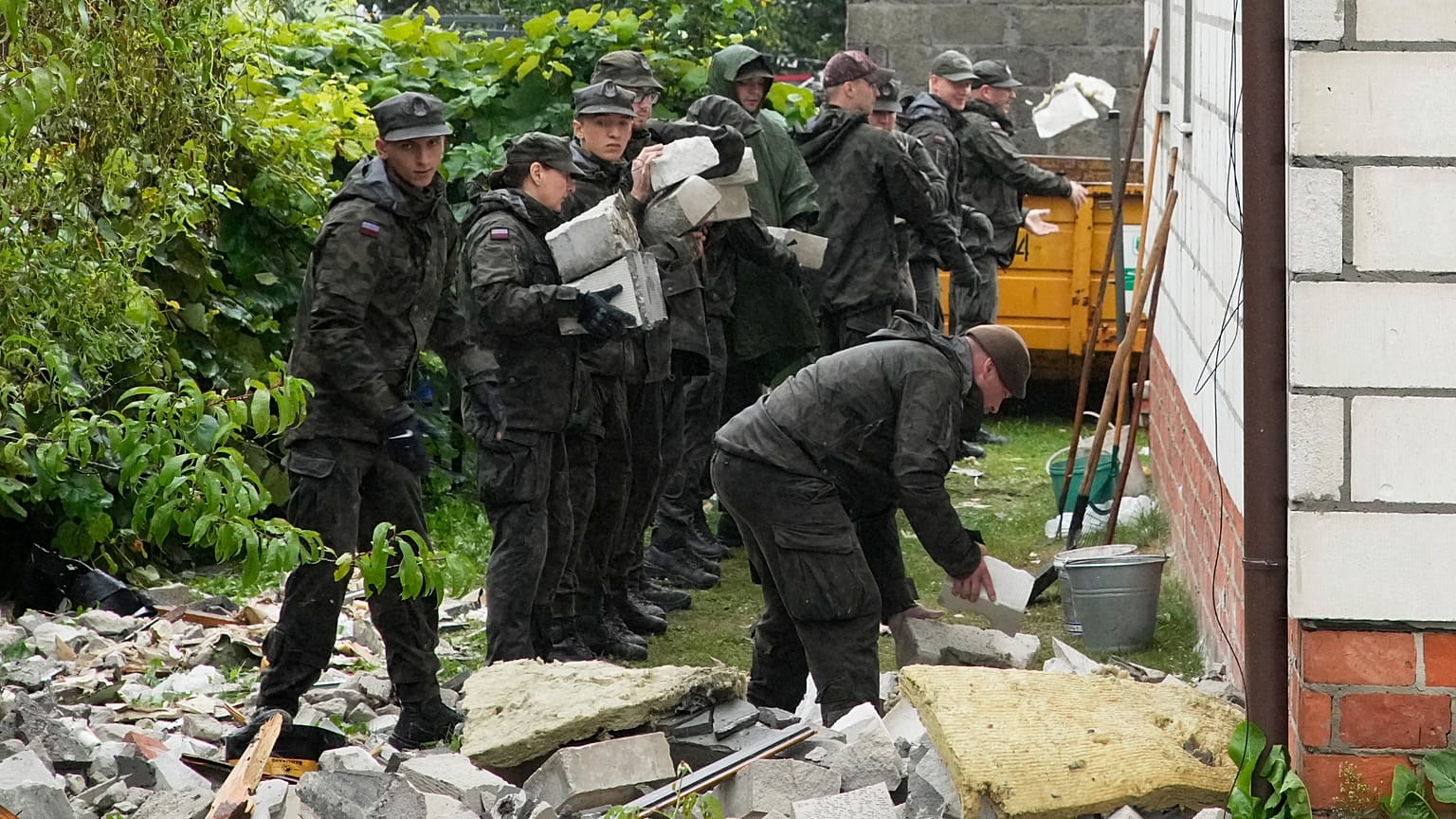 Funkcjonariusze obrony terytorialnej sprzątają gruz z zniszczonego dachu domu po ataku kilku rosyjskich dronów w Wyrykach koło Lublina w Polsce, w czwartek 11 września 2025 r.